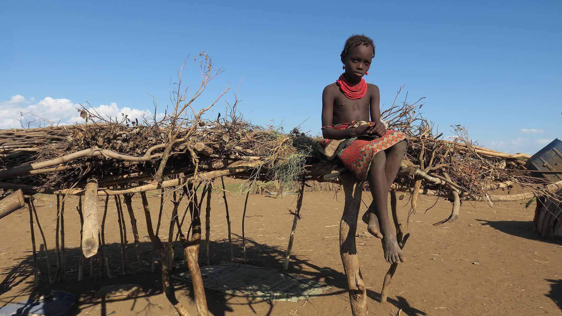 Das kleine Masai Mädchen Alaika sitzt oben auf dem geflochtenen Sonnenschutzdach. Vor zwei Jahren wäre sie fast an ihrer Beschneidung gestorben.