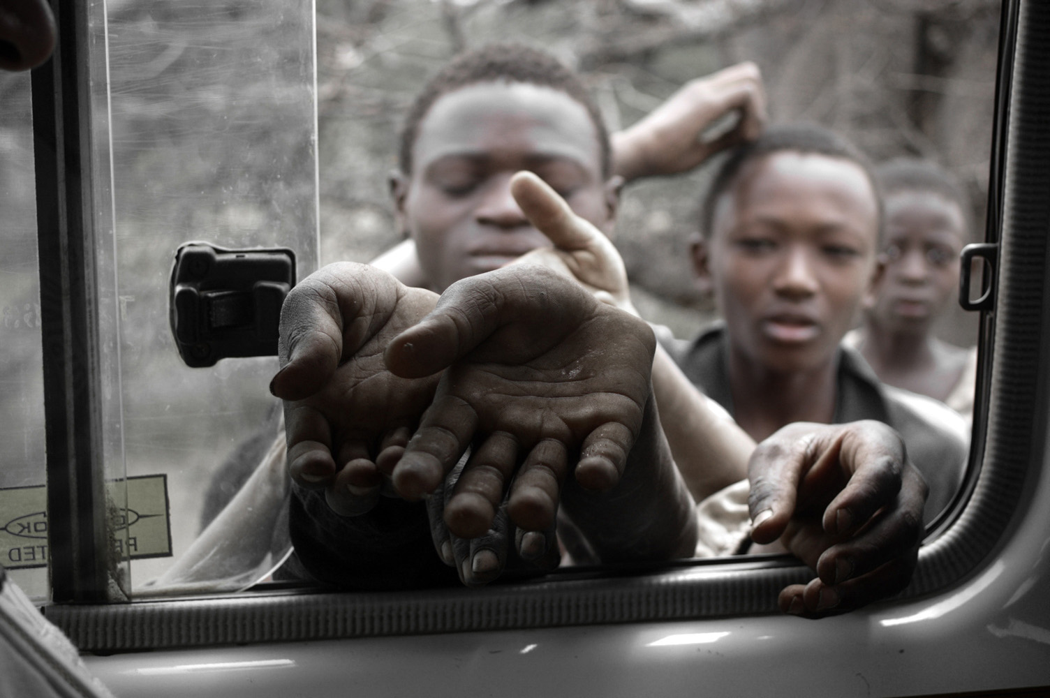 Tansanische Kinder und Jugendliche strecken ihre Hände durch ein Autofenster. Sie betteln, weil sie nichts zu essen haben.