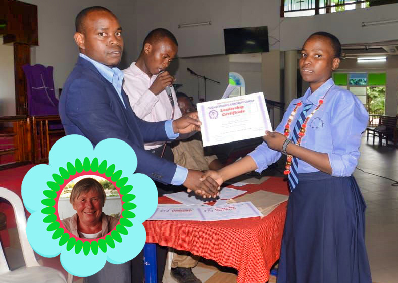 Ein Mädchen von 16 Jahren erhält eine Urkunde vom Direktor ihrer Schule. Links unten im Bild ein Portrait der Patin. Das Bild symbolisiert Zukunft durch Patenschaft.