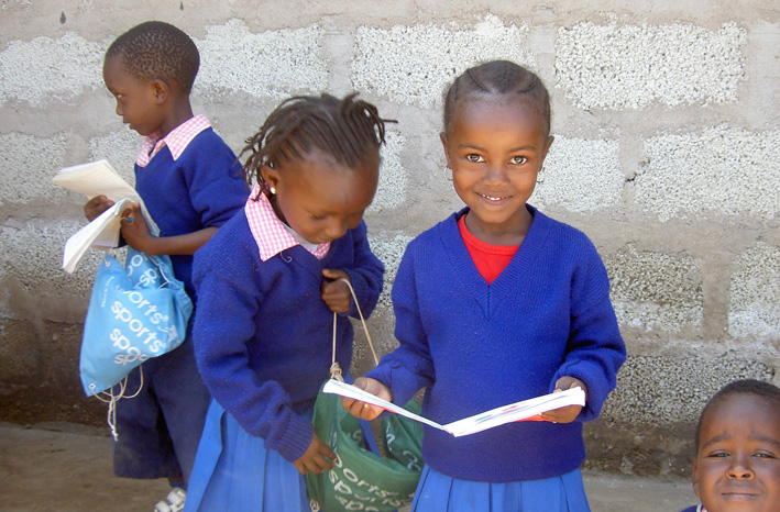 Zwei kleine afrikanische Schulmädchen, die glücklich in die Kamera schauen.