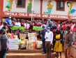 Eine Gruppe von Menschen, Lehrern und Schülern stehen vor der Schule in Tortola Nairobi. Sie haben kostenlose Hygieneartikel für die Mädchen aufgestapelt.