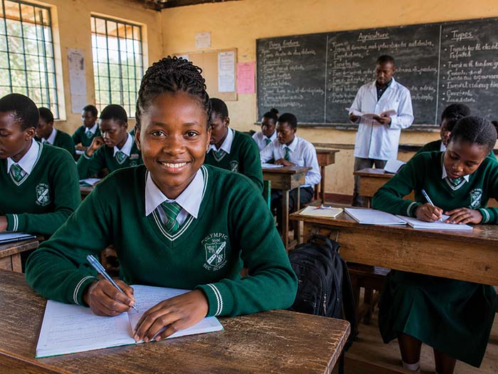 L&auml;chelnde Sch&uuml;lerin beim Lernen im Unterricht an einer Schule in Afrika.