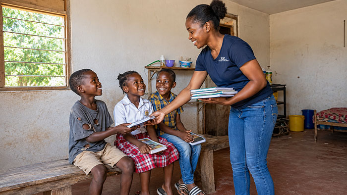 Mitarbeiterin übergibt Kindern Schulmaterialien – Kinderpatenschaften fördern Bildung in Afrika