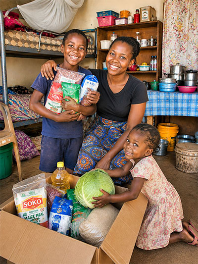 Mutter mit zwei Kindern und einer FoodBox mit Lebensmitteln in Afrika